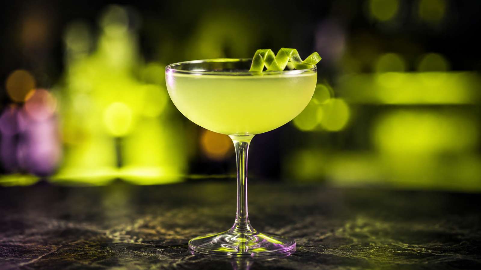 Gimlet vor extrem unscharfem Neonhintergrund in der Farbe des Drinks