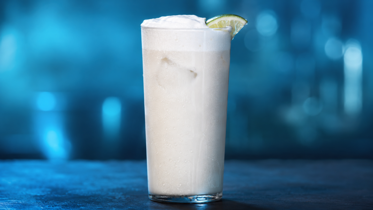 Ramos Gin Fizz vor extrem unscharfem Neonhintergrund in der Farbe des Drinks